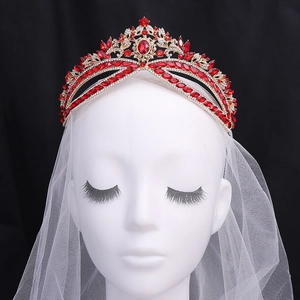Luxurious bridal tiara with red crystals and gold filigree on a white mannequin