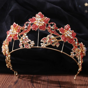 Close-up of golden bridal tiara with red floral rhinestones and baroque style details
