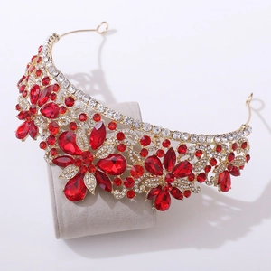 Dettaglio di una corona da sposa dorata con strass rossi su supporto per gioielli