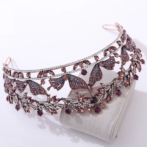 Dettaglio corona a farfalla vintage in bronzo con strass viola su supporto in velluto