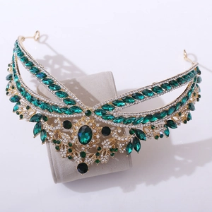 Detail of luxury baroque gold crown featuring emerald green crystals and white rhinestones