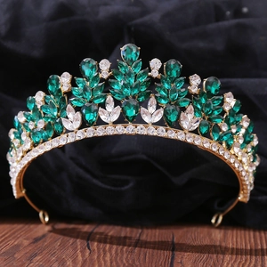 Close-up of golden bridal crown with emerald and white marquise-cut rhinestones