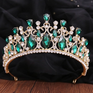 Detail of baroque gold crown featuring emerald green crystals and sparkling rhinestones
