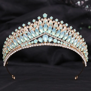Macro detail of luxury gold tiara with mint green crystals and white diamonds set on velvet