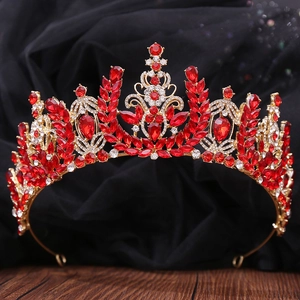 Close-up of Baroque bridal crown with red crystals and golden leaf patterns on wood