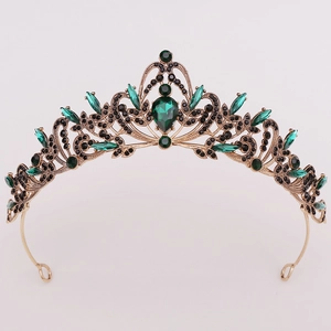Close-up of golden crown featuring emerald green gems and black crystals for bridal wear