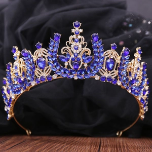 Close-up of Baroque gold crown with deep blue crystals and leaf motifs on black velvet