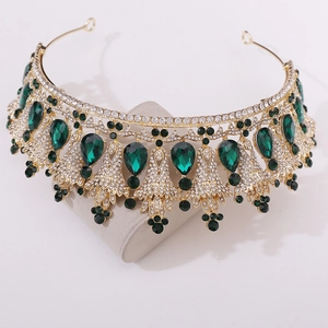 Macro detail of luxury gold bridal tiara featuring green emerald crystals and white rhinestones