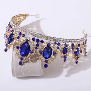 Detailed side view of Baroque gold bridal crown with deep blue crystals on a display stand