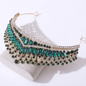 Detailed close-up of emerald green crystals and sparkling rhinestones on golden bridal tiara