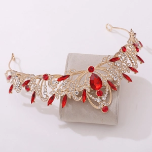 Close-up of golden crown featuring teardrop red crystal and intricate leaf hollow pattern