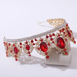 Macro detail of baroque gold tiara featuring ruby-red crystals and intricate rhinestone patterns