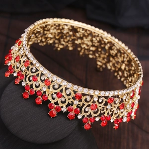 Détail d'une couronne baroque dorée ornée de strass rouges et blancs sur fond sombre