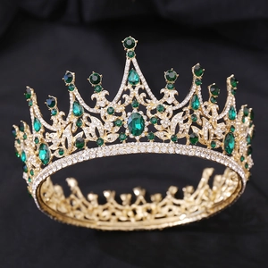 Gros plan sur une couronne baroque dorée avec cristaux vert émeraude sur noir