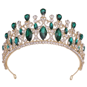 Macro shot of gold baroque crown with emerald green crystals and sparkling rhinestones
