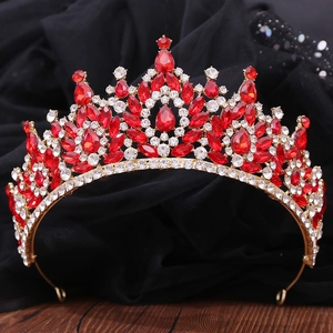 Close-up of golden crown featuring red teardrop rhinestones and sparkling crystals