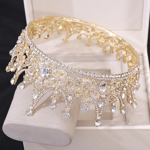 Gros plan sur une couronne de mariée dorée avec motifs baroques et cristaux en poire