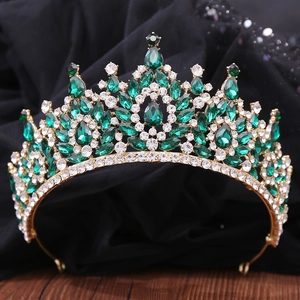 Detailed front view of a baroque gold tiara featuring emerald and clear crystals