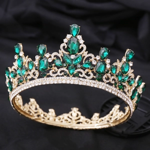 Macro shot of luxury gold baroque tiara featuring emerald crystals and white rhinestones