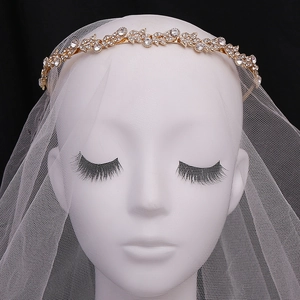 Dettaglio del cerchietto dorato con strass su velo da sposa in pizzo bianco