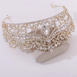 Close-up of luxury gold bridal crown with white rhinestones and clear crystals on display