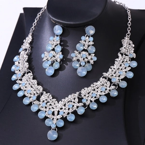Macro shot of silver bridal jewelry set featuring light blue crystals and drop earrings