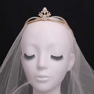 Close-up of golden bridal crown with sparkling zircons and delicate white bridal tulle veil