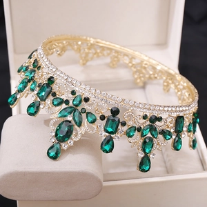 Close-up of luxury Baroque gold crown with emerald green crystals and white rhinestones