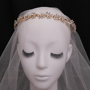 Dettaglio del cerchietto da sposa dorato con motivo a foglie e strass scintillanti