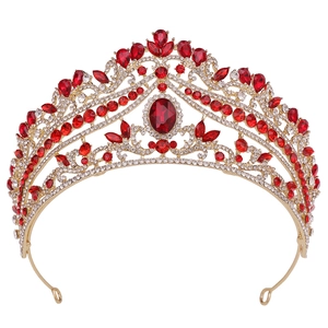Detailed close-up of a gold bridal crown featuring large red rubies and clear rhinestones
