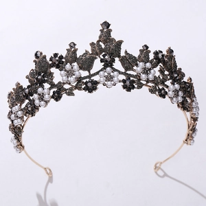 Close-up of vintage baroque crown featuring black crystals and white pearls on antique gold