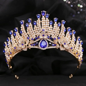 Detailed close-up of a gold baroque crown featuring sparkling blue crystals on black fabric