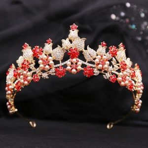 Macro detail of golden bridal tiara with red crystals, white pearls and floral tulip patterns