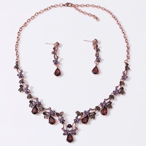 Detail of vintage necklace and earrings set with red crystals and purple rhinestones
