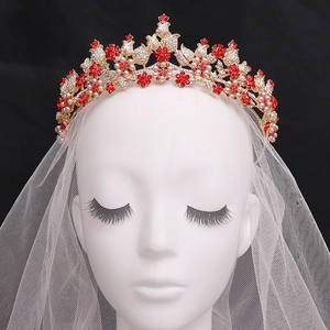 Close-up of bridal gold crown with red crystal flowers, white pearls and sparkling zircons