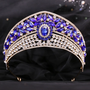 Close-up of royal bridal crown with blue gemstones and rhinestones on black velvet