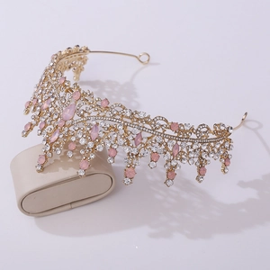 Détail de la couronne de mariée dorée avec des gemmes roses et cristaux sur un coussin