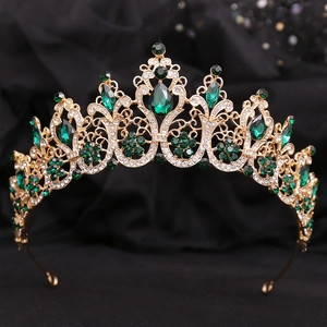 Detailed view of the gold baroque crown featuring emerald green teardrop crystals