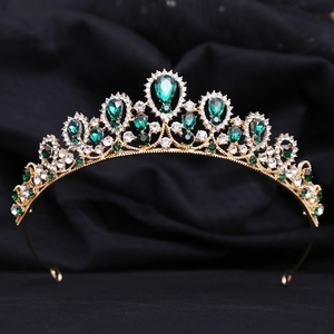 Macro detail of royal gold tiara featuring teardrop green crystals and white rhinestones
