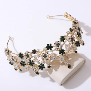 Macro detail of bridal crown with dark green crystals and pink pearls on gold frame