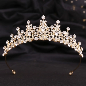 Macro detail of gold bridal crown with crystal marquise stones on black fabric background