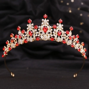 Detailed macro shot of vintage gold tiara with red rhinestones on black background