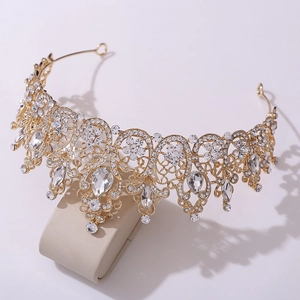 Golden Baroque bridal crown with shimmering crystals and pear-shaped gems on a display stand