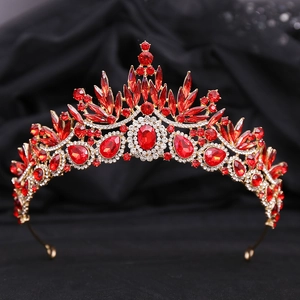 Detail of a red crystal baroque crown with gold leaf accents on black velvet background