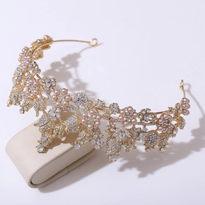 Close-up of golden bridal headband with pink pearls, crystals, and floral leaf details