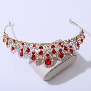 Close-up of golden crown with teardrop red rhinestones on a jewelry display stand