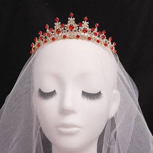 Baroque gold bridal tiara with red gemstones and white lace veil on dark background