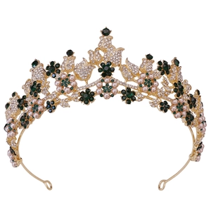 Close-up of golden bridal headband with emerald green crystals and white pearls