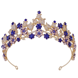 Close-up of golden bridal tiara with deep blue rhinestone flowers and white pearls