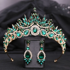 Macro shot of emerald green crystal tiara and matching earrings on black fabric